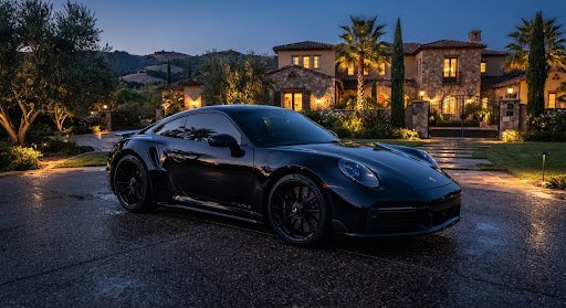 Black sports car in front of a house at dusk